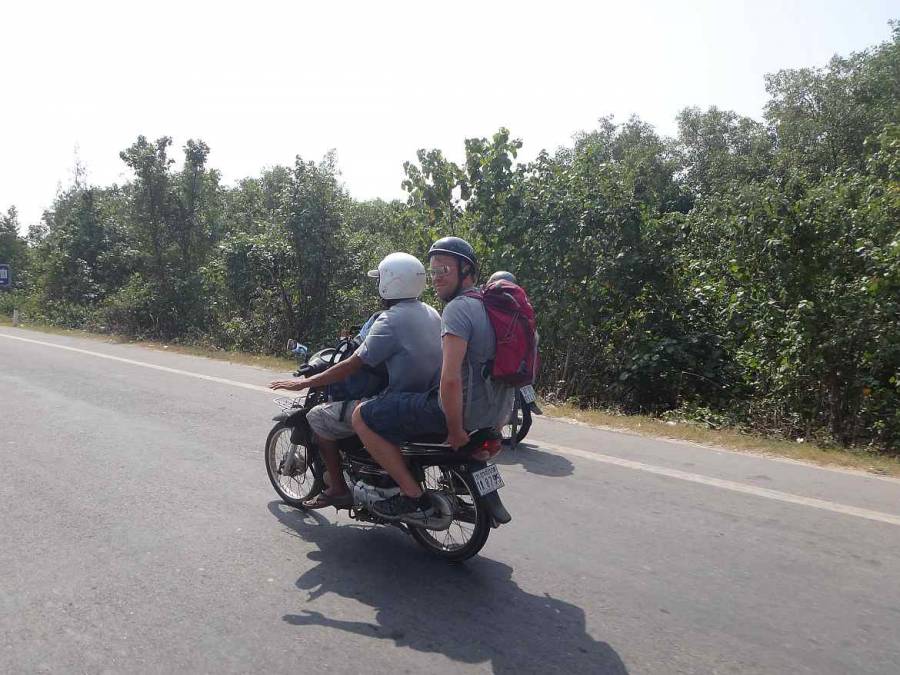 Kambodscha | Moped-Taxi bei der Fahrt über die Grenze von Kambodscha nach Vietnam. Henning hinten auf dem Moped eines kambodschanischen Fahrers