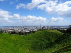 Neuseeland | Nordinsel, Panorama vom Mount Eden in Auckland über einen mit sattgrüner Wiese bewachsenen Vulkankrater auf die Skyline und den Hafen von Auckland