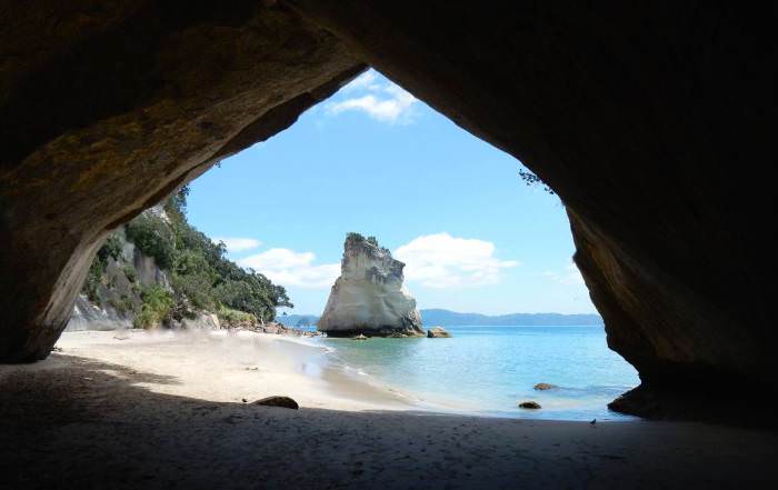Neuseeland | Nordinsel, Cathedral Cove in der Coromandel. Blick durch die Höhle auf das türkisfarbene Meer und die Kaarststeine auf der anderen Seite. Eine der Top-Sehenswürdigkeiten & Highlights der Camping-Tour