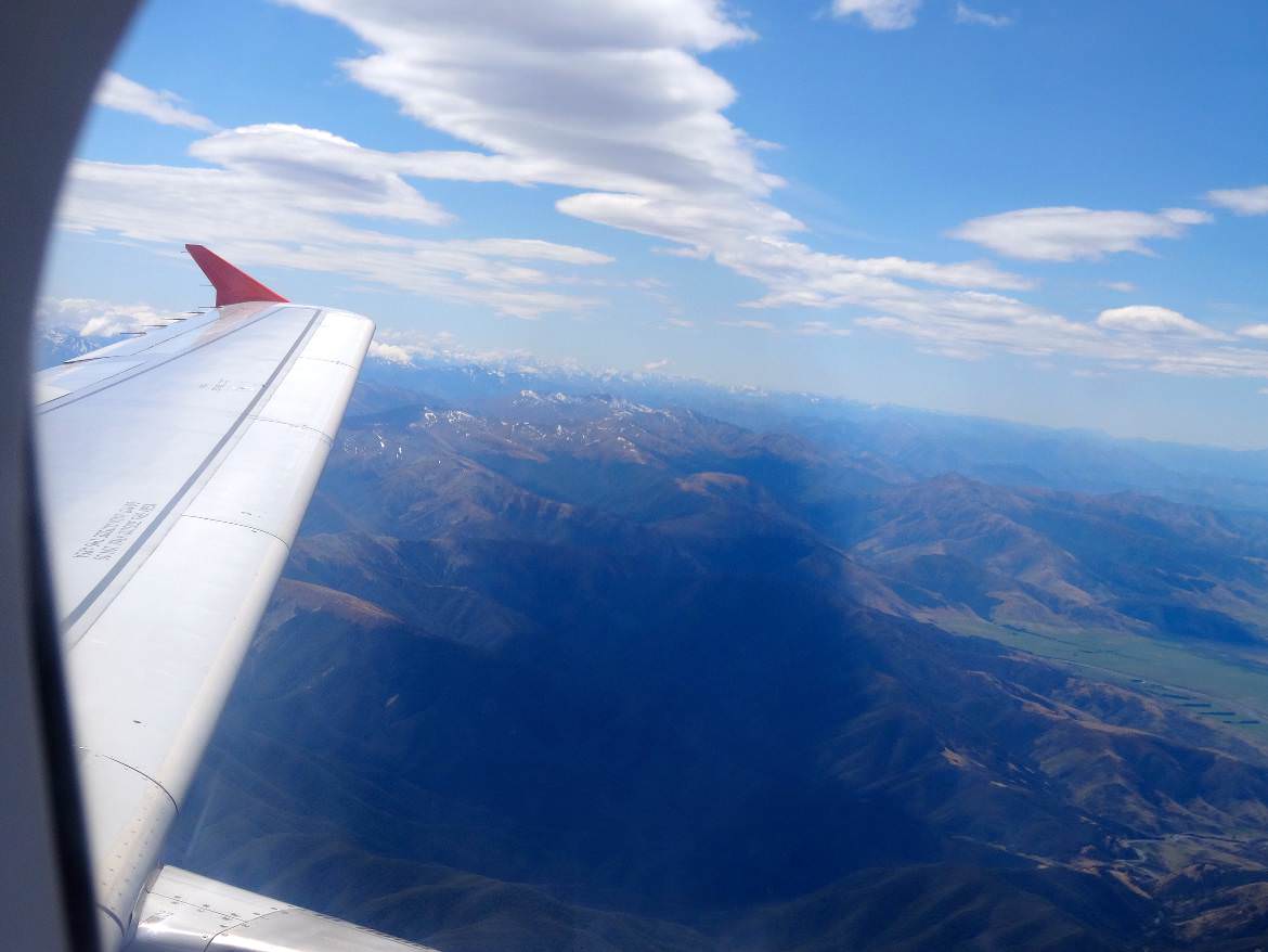 Neuseeland | Südinsel, Landeanflug Christchurch die Erste. Blick aus dem Fenster des Fliegers auf den Flügel, blauen Himmel und die schneebedeckten Alpen. Einige Tipps und den Reisebericht zur Rundreise haben wir zusammen gefasst
