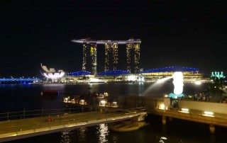 Singapur | Blick auf das Marina Bay Sands und Merlion bei Nacht von bunten Lichtern beleuchtet