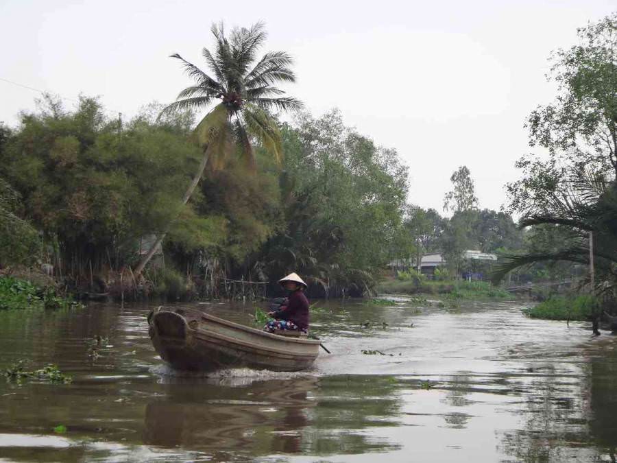 Vietnam | Süden, Fortbewegungsmittel im Mekong bei Can Tho. Eine Frau sitzt in ihrem Boot inmitten einer kleinen Nebenstraße des Mekong umgeben von sattgrünem Urwald