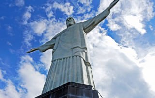 Brasilien | Rio de Janeiro, Die imposante Jesusstatue auf dem Corcovado, hier aus seitlicher Perspektive vor blauem Himmel aufgenommen, ist das vermutlich am einfachtsen zu Erreichende unter den Neuen Sieben Weltwundern