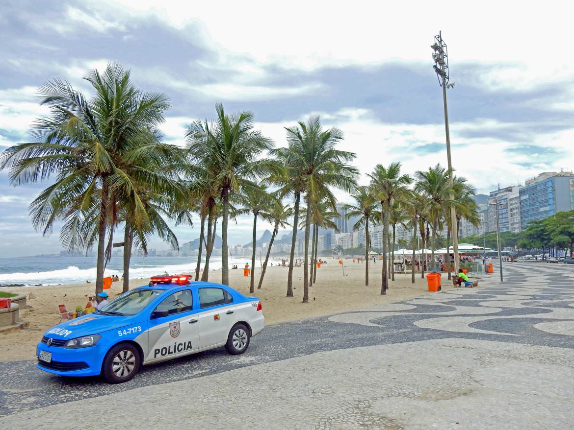 Rio de Janeiro | Sicherheit: blau-weißer Polizeiwagen vor den Palmen der Copacabana