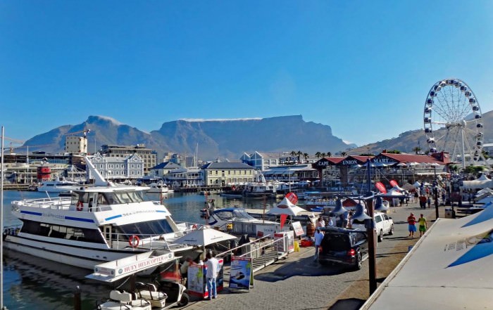 Südafrika | Kapstadt, Panorama in der V&A Waterfront mit dem Tafelberg im Hintergrund. Boote, Restaurants, Shops, Touristen bei blauem Himmel