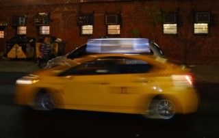 Tipps wie Du weltweit sicher und guenstig ein Taxi findest. Hier ein gelbes Taxi in einer Großstadt von Motion Blur