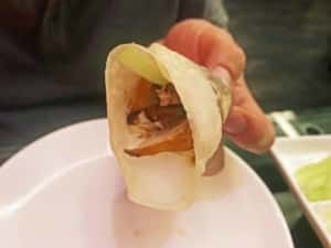 Peking Ente Essen: Gerollter Wrap gefüllt mit Entenbrust, Gurke, Lauch und Sojasauce