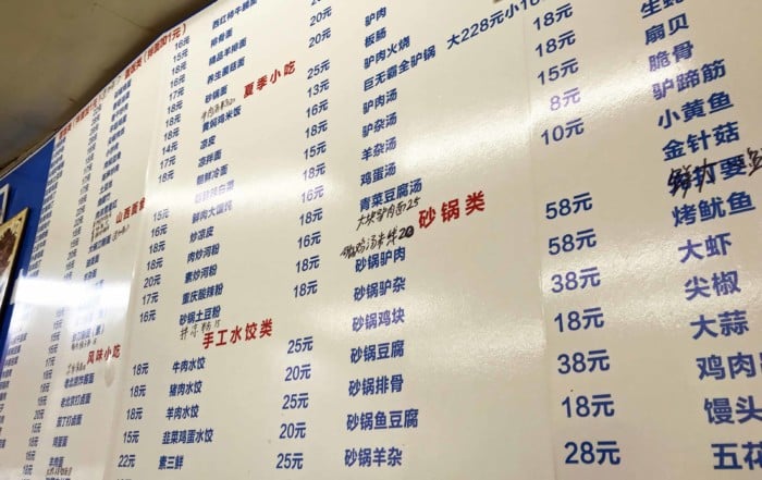 Chinesische Speisekarte in einem einfachen Restaurant in Peking. Schriftzeichen auf einer Tafel an der Wand